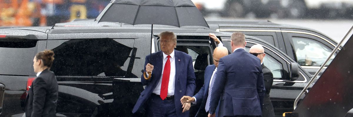 Former U.S. President Donald Trump holds an umbrella