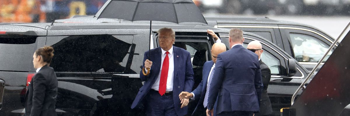Former U.S. President Donald Trump holds an umbrella