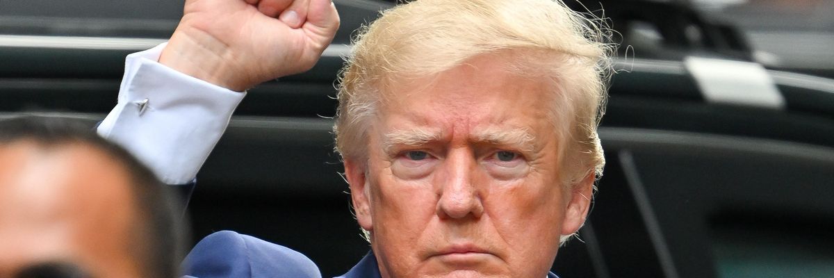 Former U.S. President Donald Trump leaves Trump Tower with his fist raised.