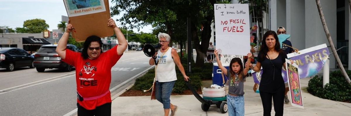 Four people march against fossil fuels including a mother and child.