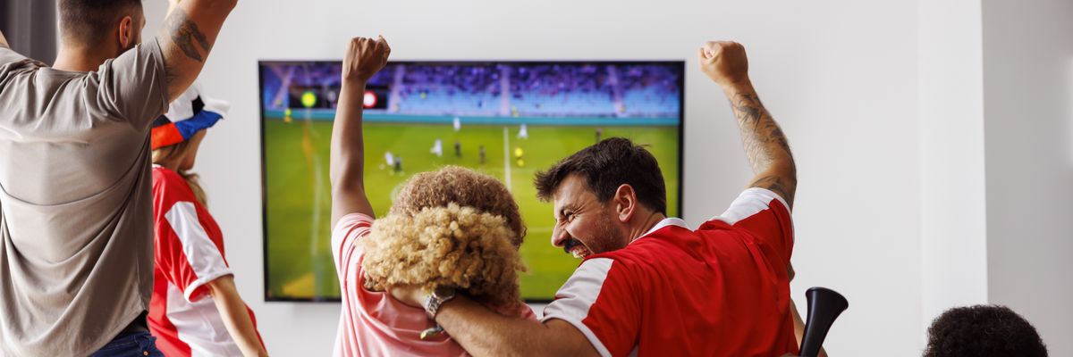 Friends cheering while watching football on TV