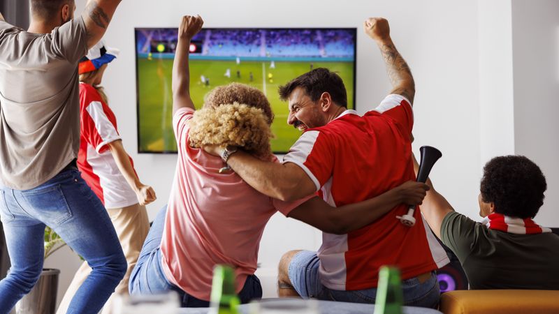 Friends cheering while watching football on TV