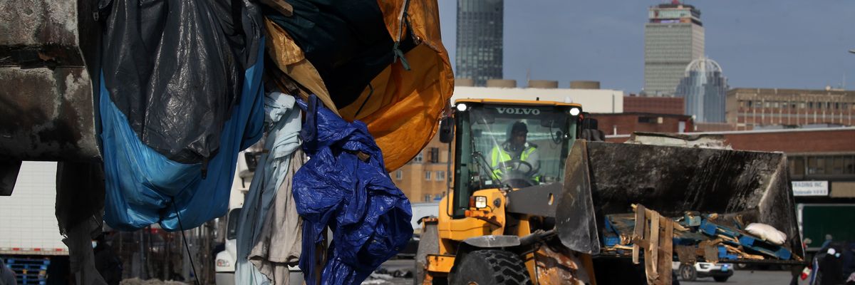 Front-end loader clearing belongings at homeless encampment in Boston.