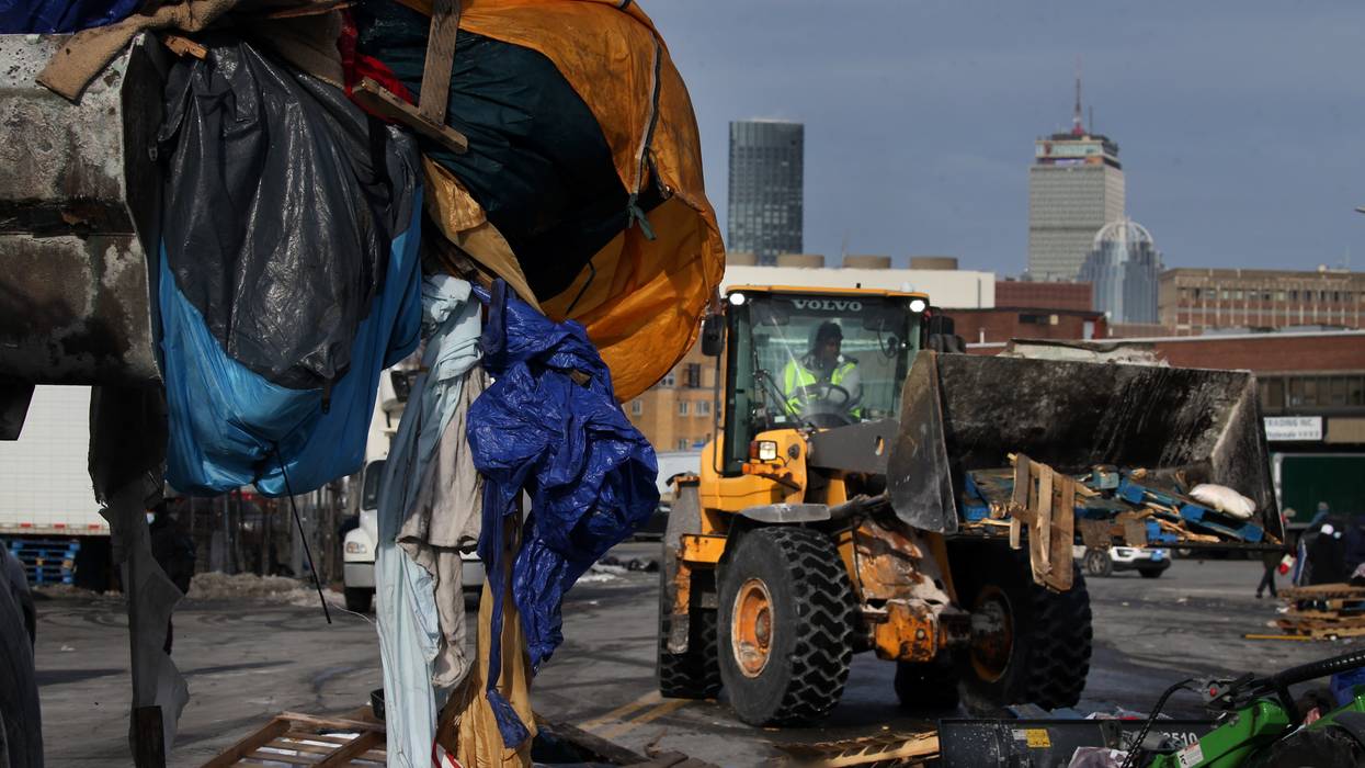 Front-end loader clearing belongings at homeless encampment in Boston.