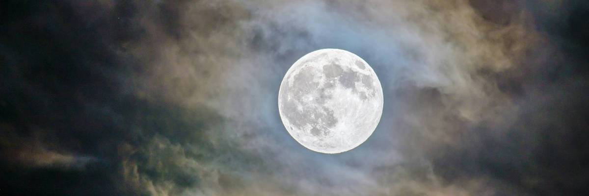 Full moon surrounded by clouds.