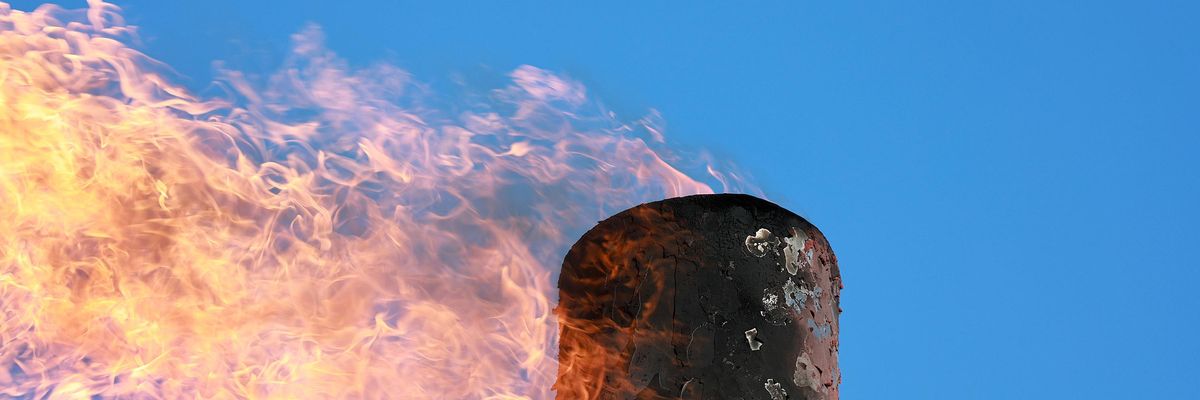 Gas is flared against a blue sky.