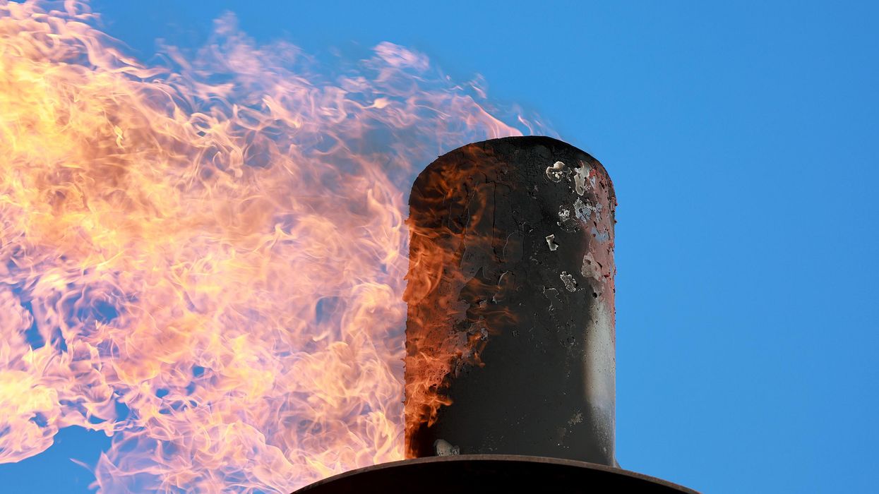 Gas is flared against a blue sky.