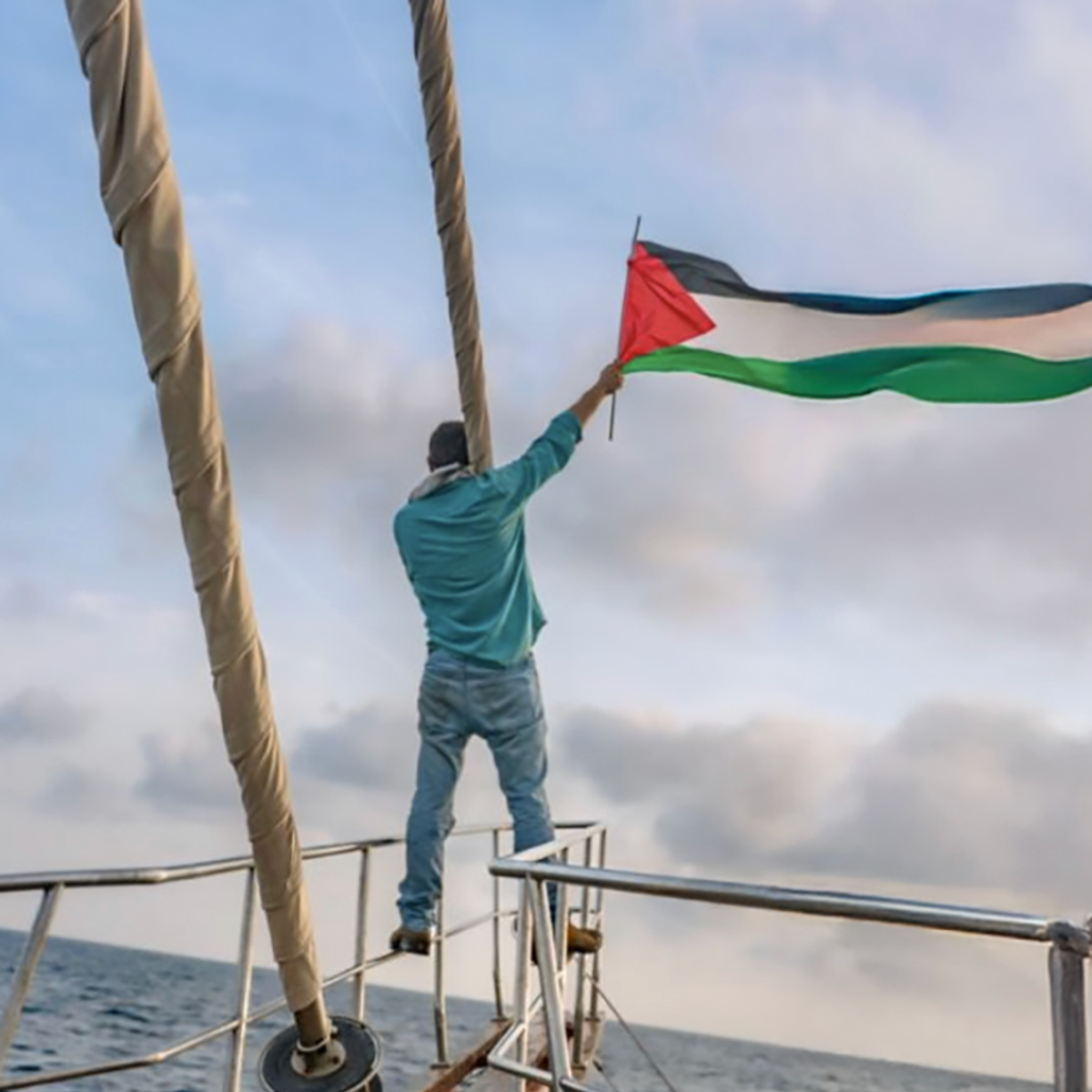 Gaza Freedom Flotilla member waves Palestinian flag from a boat