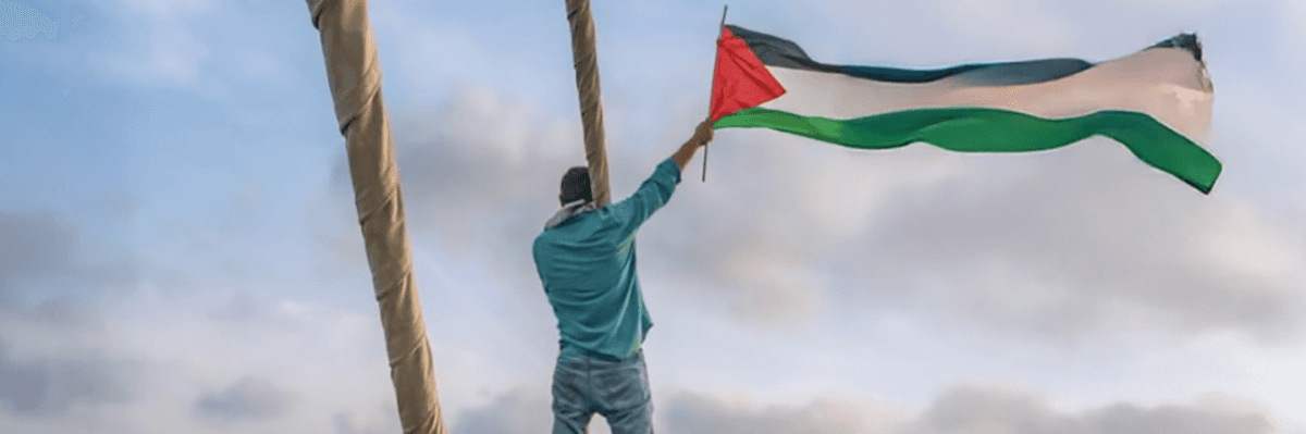 Gaza Freedom Flotilla member waves Palestinian flag from a boat