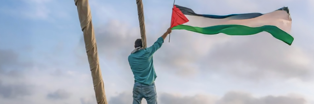 Gaza Freedom Flotilla member waves Palestinian flag from a boat