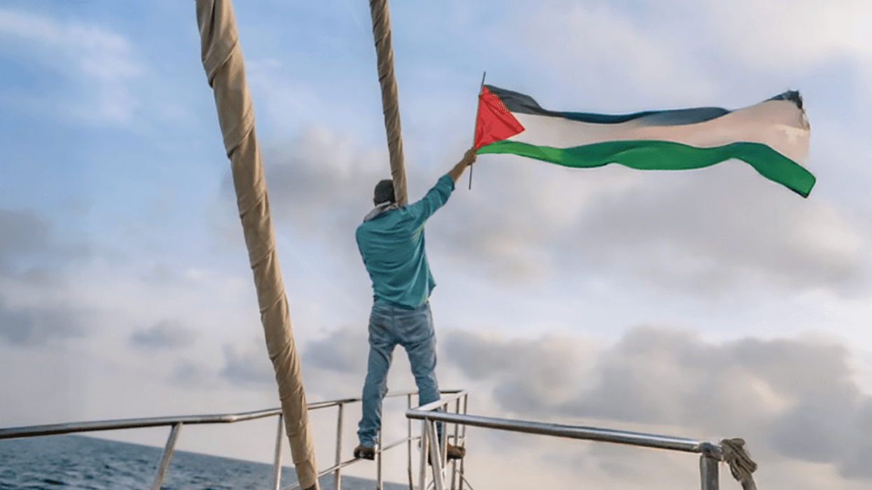 Gaza Freedom Flotilla member waves Palestinian flag from a boat