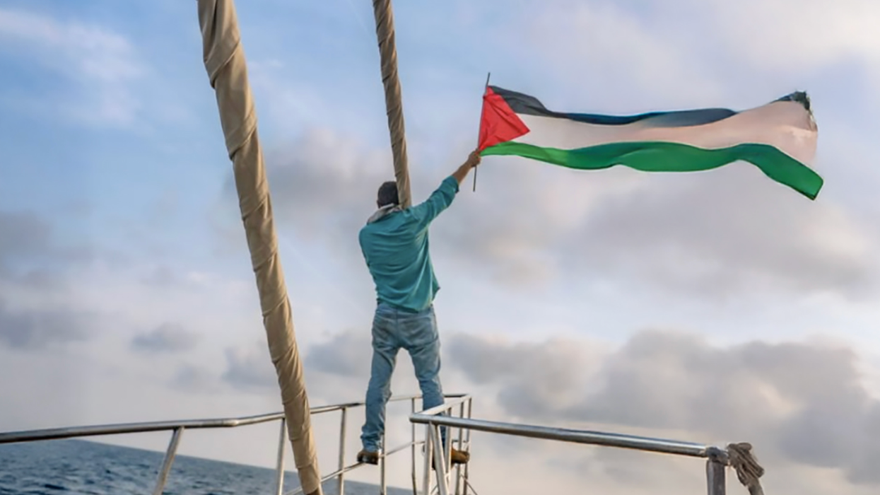 Gaza Freedom Flotilla member waves Palestinian flag from a boat