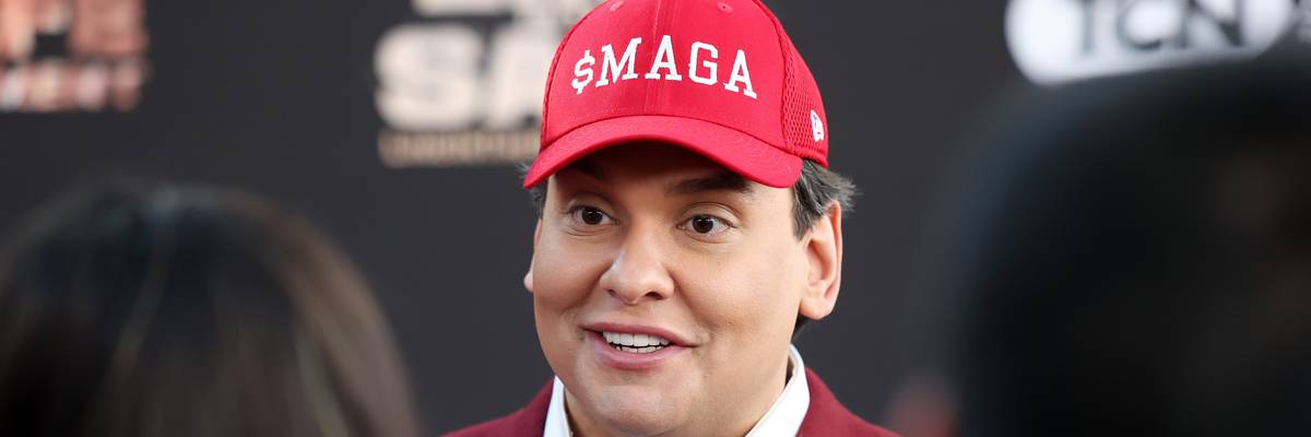 George Santos wears a hat reading "$MAGA"
