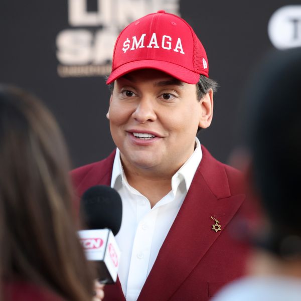 George Santos wears a hat reading "$MAGA"