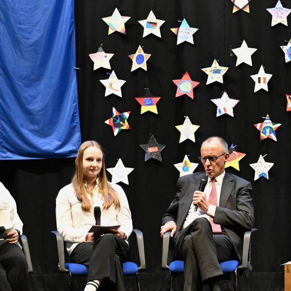 German Chancellor Friedrich Merz sits next to high school students