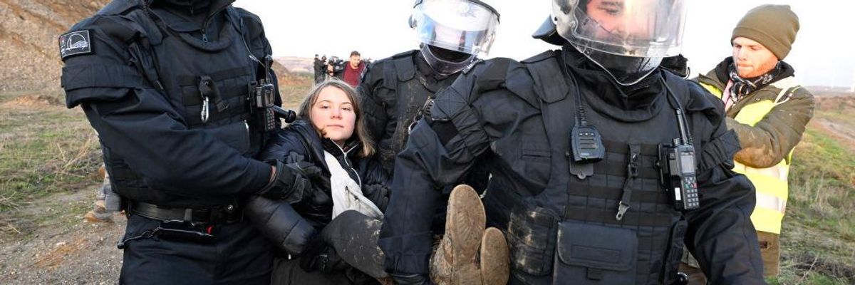 German police officers carry Swedish climate activist Greta Thunberg away from the edge of a coal mine