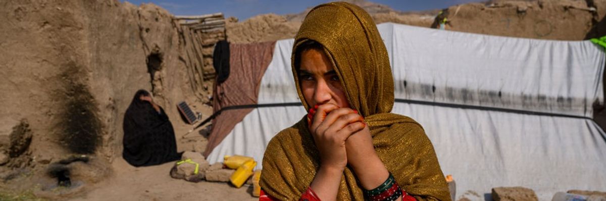 Girl displaced by drought stands in front of tent in Afghanistan.