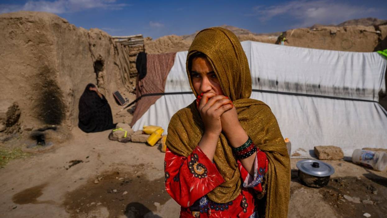 Girl displaced by drought stands in front of tent in Afghanistan.
