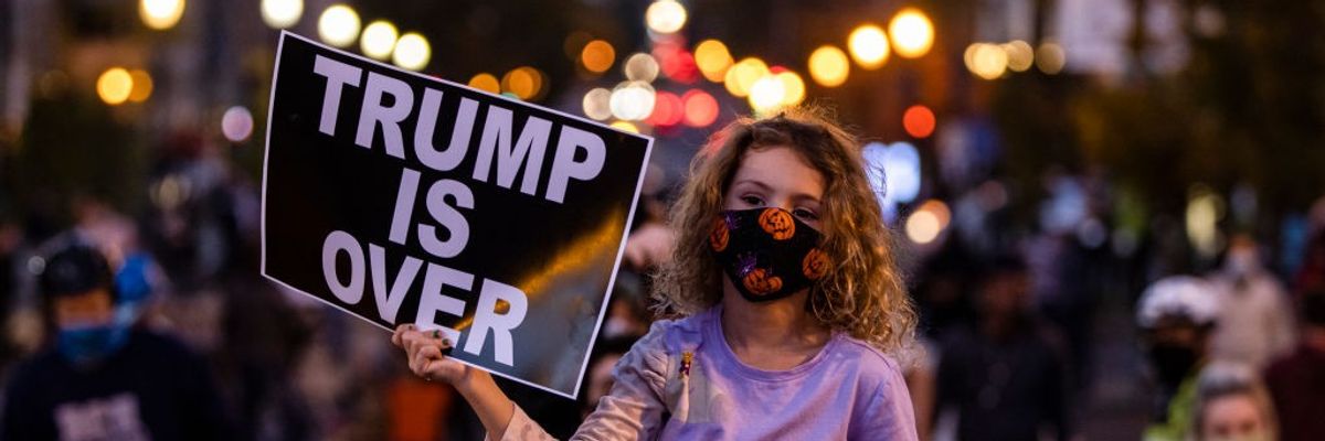 Girl holds sign "Trump Is Over"