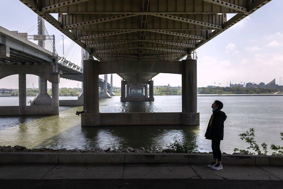 Girl stands under a bridge over a river