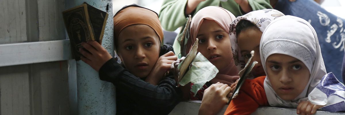 Girls impacted by the war in Yemen wait to receive food from a local charity