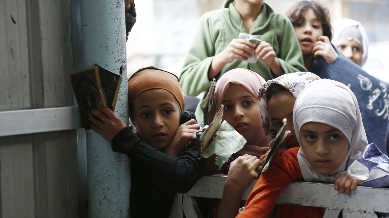 Girls impacted by the war in Yemen wait to receive food from a local charity