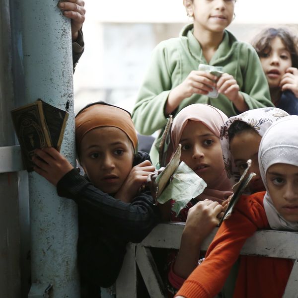 Girls impacted by the war in Yemen wait to receive food from a local charity