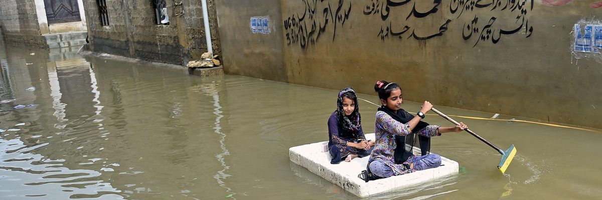 Girls use a temporary raft across a flooded street in a residential area after heavy monsoon rains in Karachi on July 26, 2022