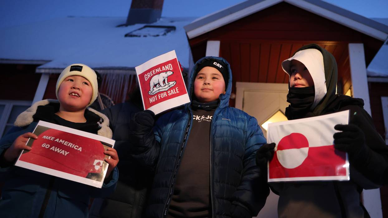 Greenland children hold signs reading "Make America Go Away" and "Greenand Not for Sale"