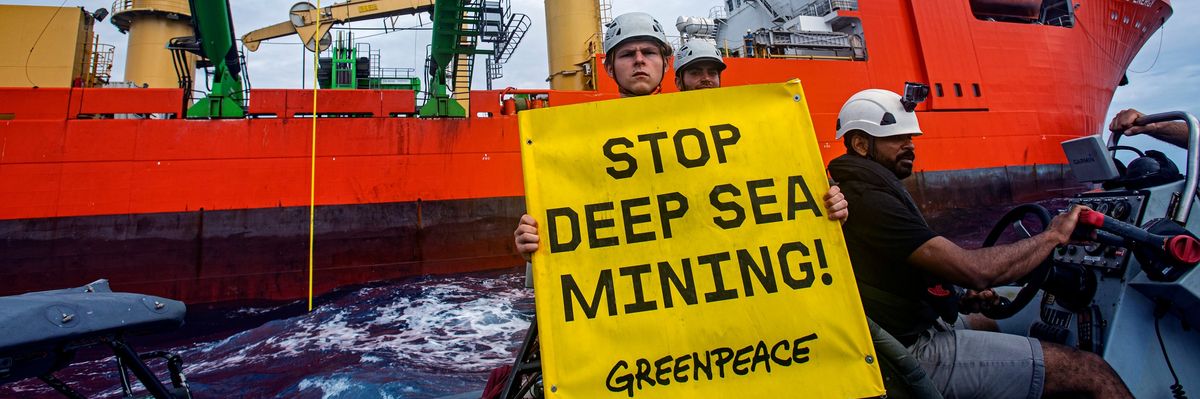 Greenpeace activist holding sign "Stop Deep Sea Mining"