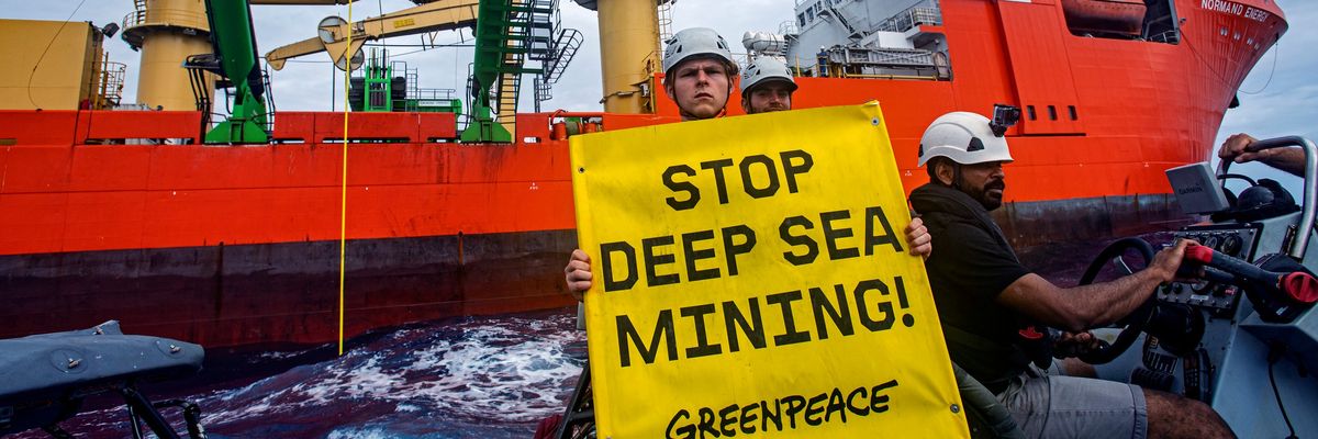 Greenpeace activist holding sign "Stop Deep Sea Mining"