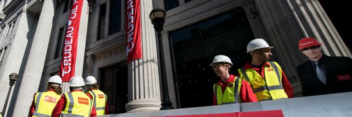Greenpeace activists unfurl banners after building a wood and card 'oil pipeline' outside the Canadian High Commission, Canada House, to protest against the Trudeau government's plans to build an oil pipeline in British Columbia on April 18, 2018 in London.