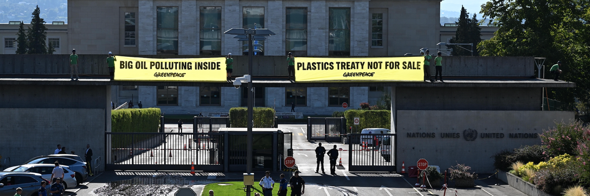 Greenpeace activists unfurl banners reading "Big Oil Polluting Inside" and "Plastics Treaty Not for Sale"