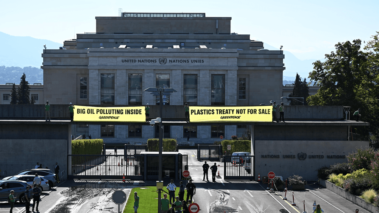 Greenpeace activists unfurl banners reading "Big Oil Polluting Inside" and "Plastics Treaty Not for Sale"
