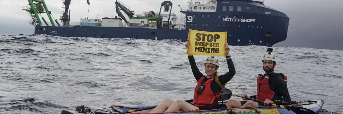 Greenpeace kayaktivists hold up a sign reading "stop deep sea mining" near an exploration ship