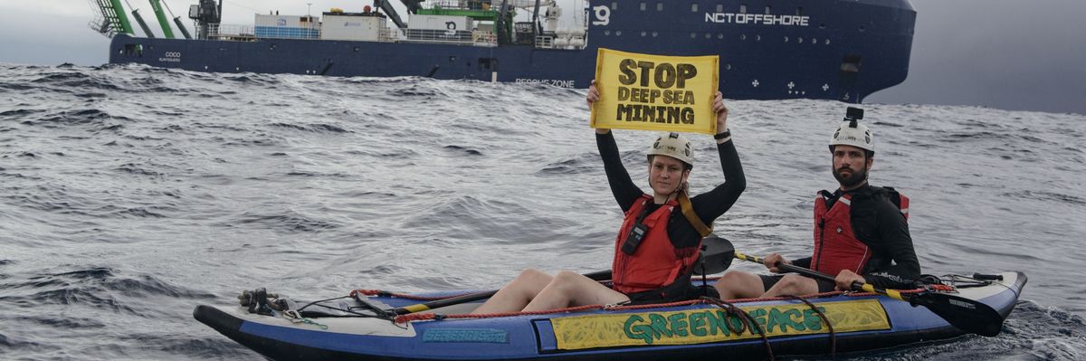 Greenpeace kayaktivists hold up a sign reading "stop deep-sea mining" near an exploration ship