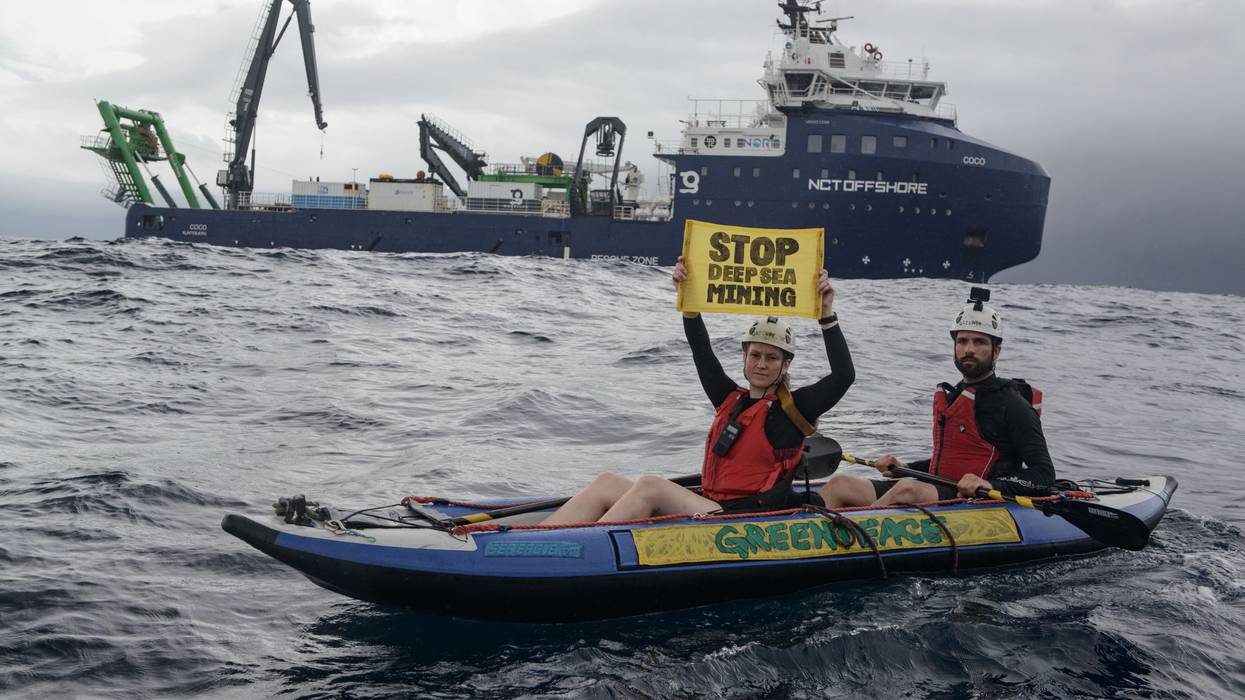Greenpeace kayaktivists hold up a sign reading "stop deep-sea mining" near an exploration ship