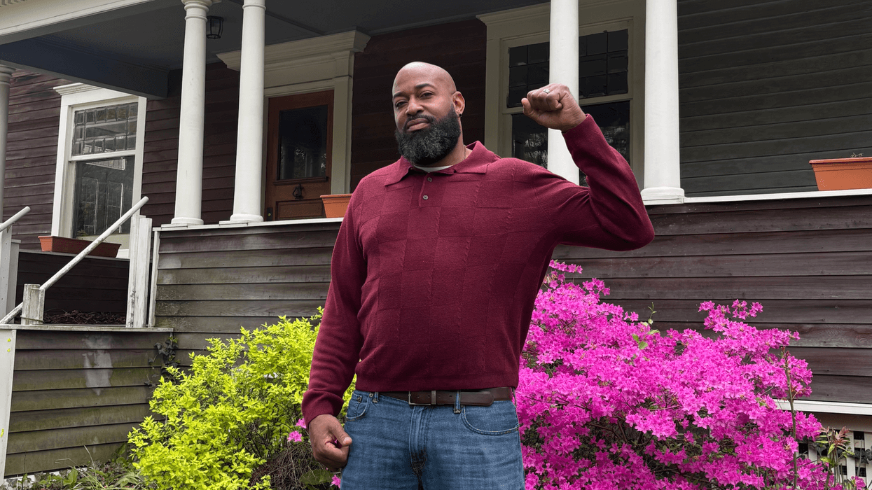 Greg Levy stands outside John Brown's house with his fist raised