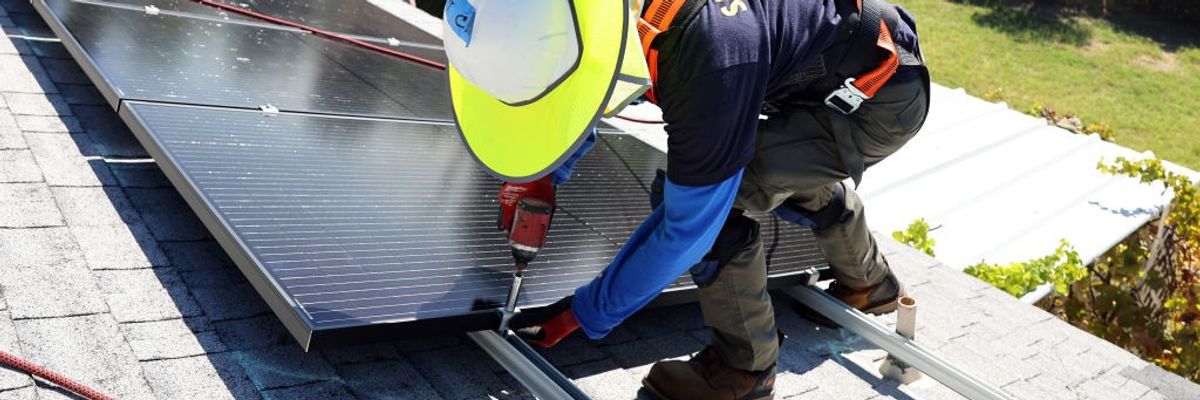 GRID Alternatives employee Tony Chang installs no-cost solar panels on the rooftop