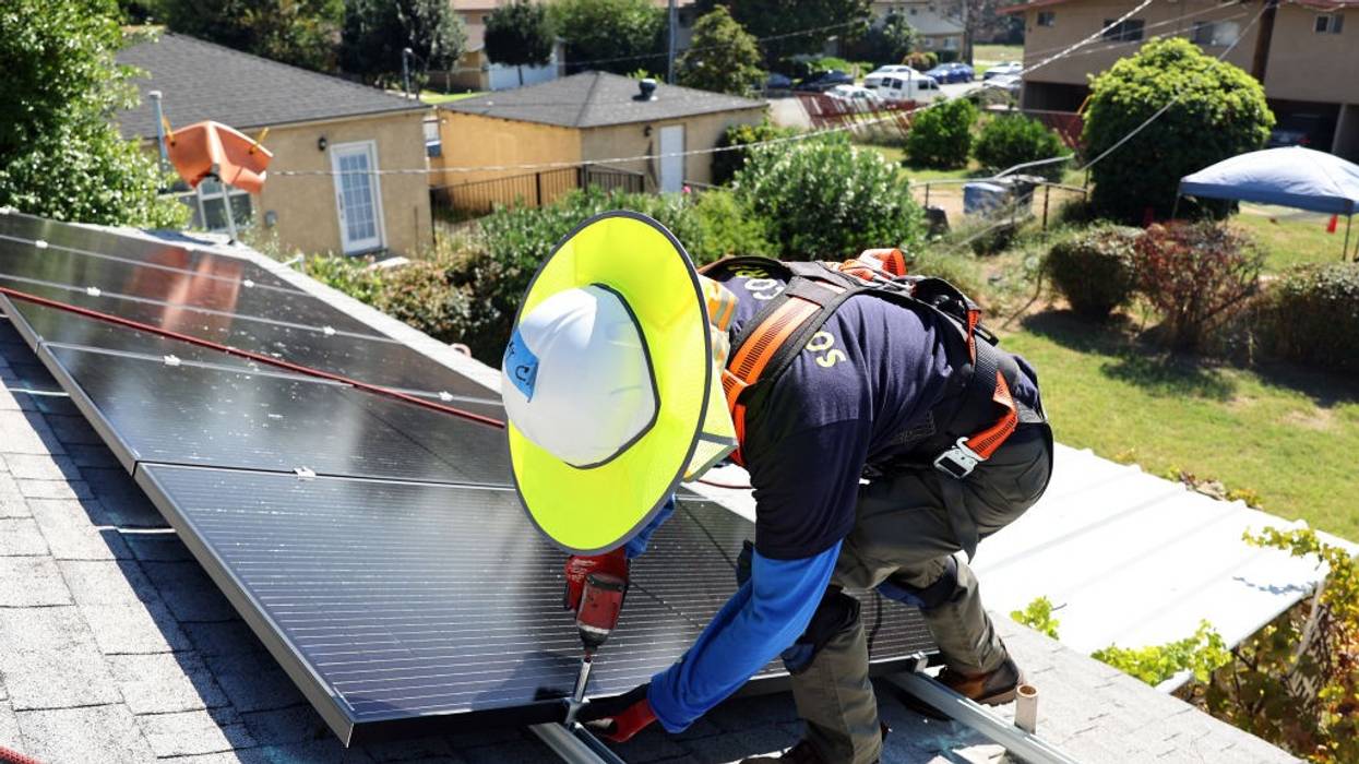 GRID Alternatives employee Tony Chang installs no-cost solar panels on the rooftop
