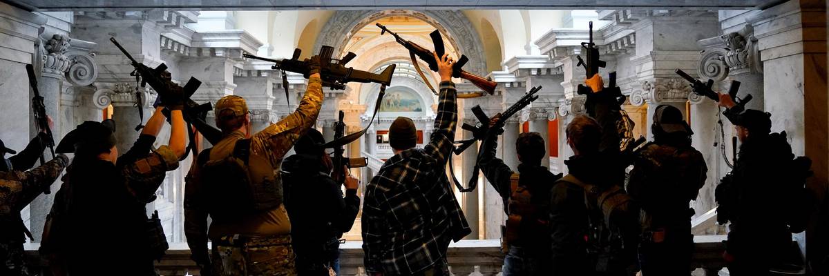 Gun rights activists lift guns in silhouette.