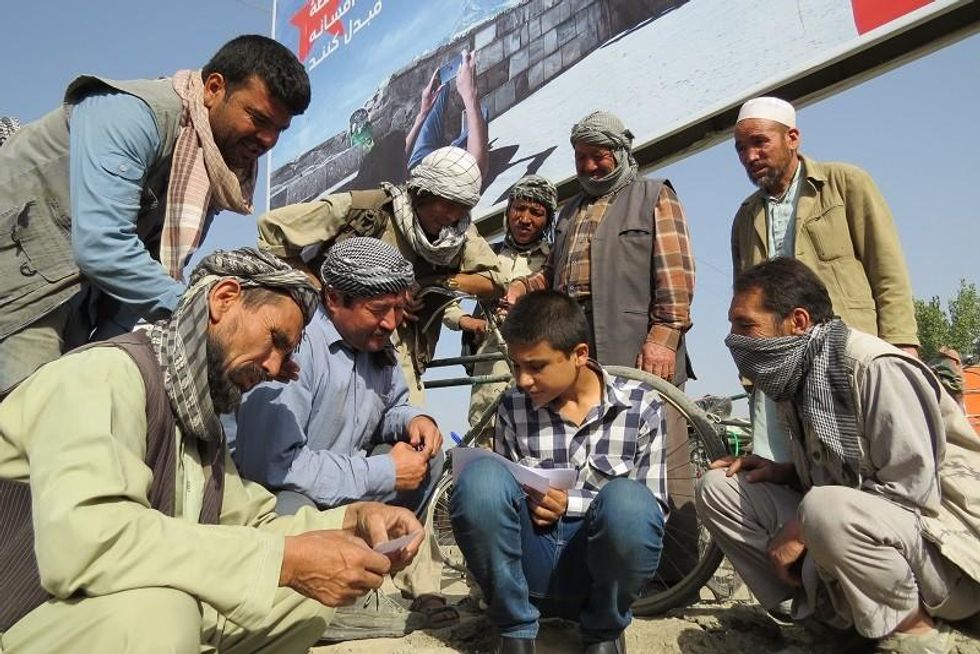 Habib, with pen and paper, making an invitation list of 100 Afghan labourers with whom he and other Afghan street kids will share a meal.
