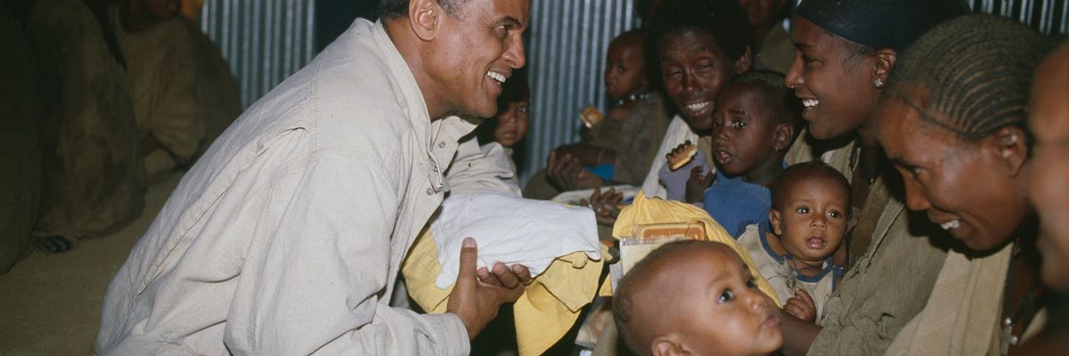 Harry Belafonte helps give out food to women and children in Ethiopia funded by sales of his record USA For Africa