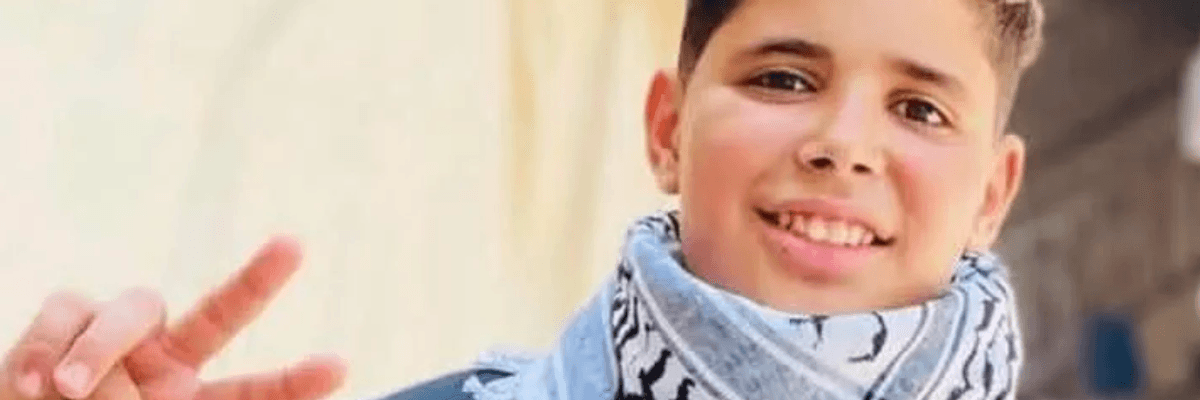 Hassan Ayyad smiling and wearing a keffiyeh while flashing a peace sign