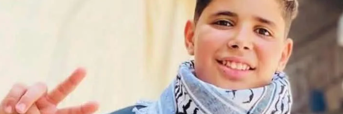 Hassan Ayyad smiling and wearing a keffiyeh while flashing a peace sign