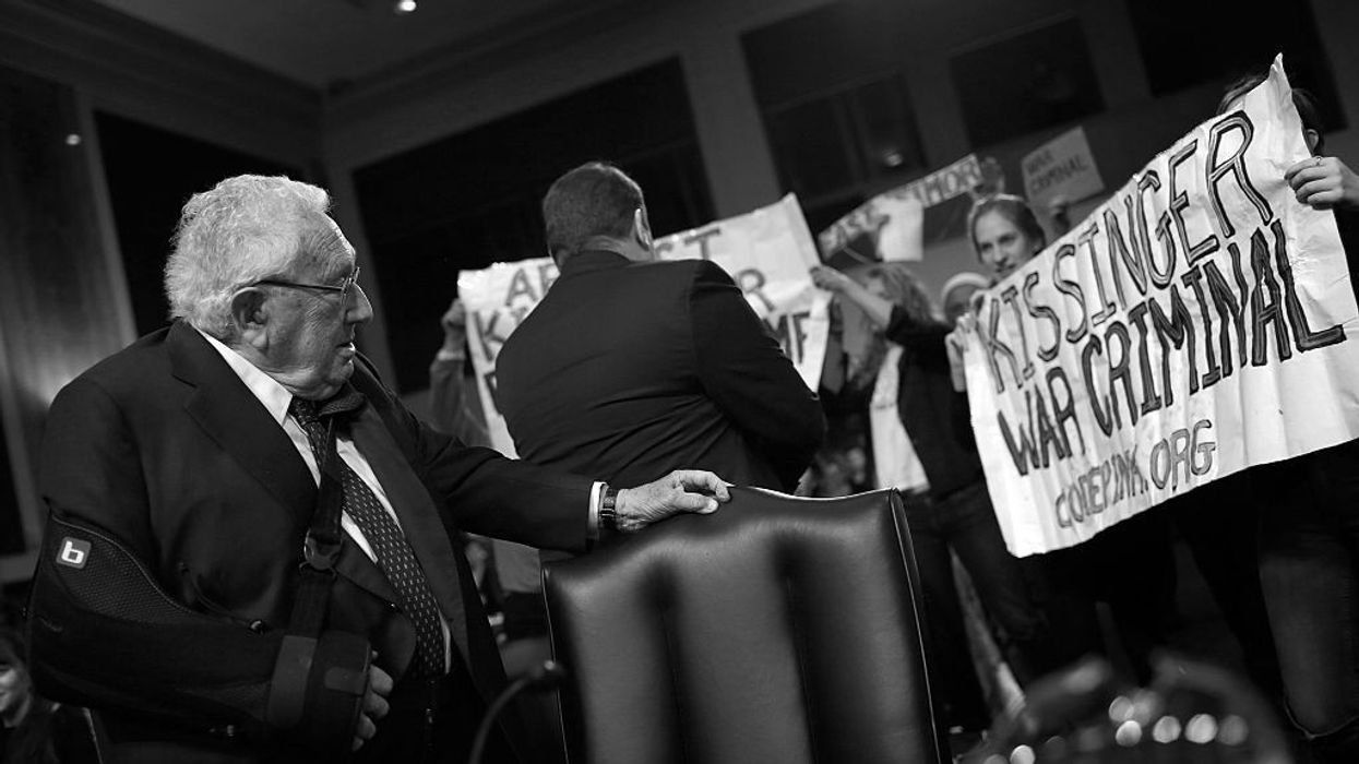 Henry Kessinger confronted by a sign reading, "Kissinger: War Criminal"
