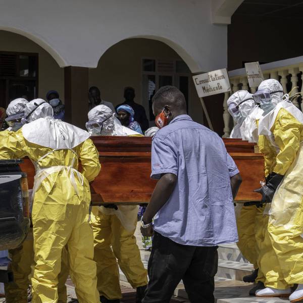 Hospital workers in protective gear move a coffin of a suspected Ebola victim