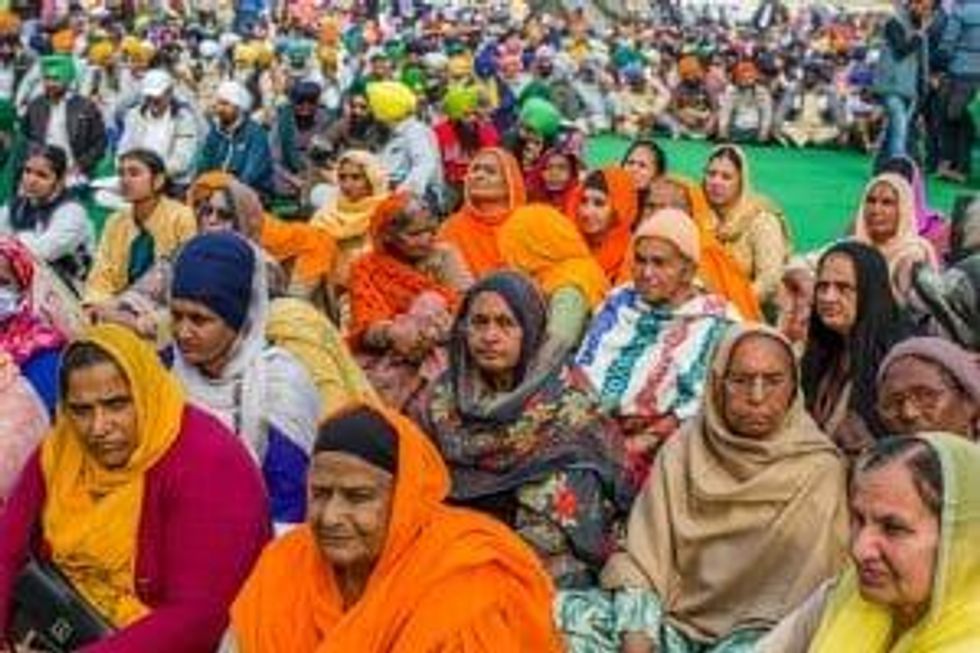 hundreds of women sit on the ground at a protest in India.