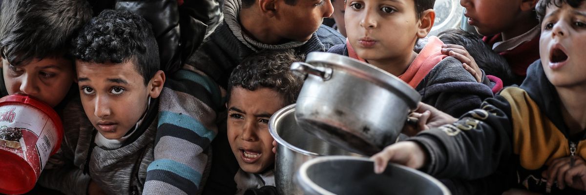 Hungry Palestinian children hold out empty pots to get donated food in Rafah.