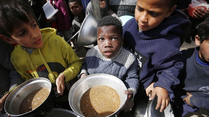 Hungry Palestinian children holding pots receive food aid in Gaza